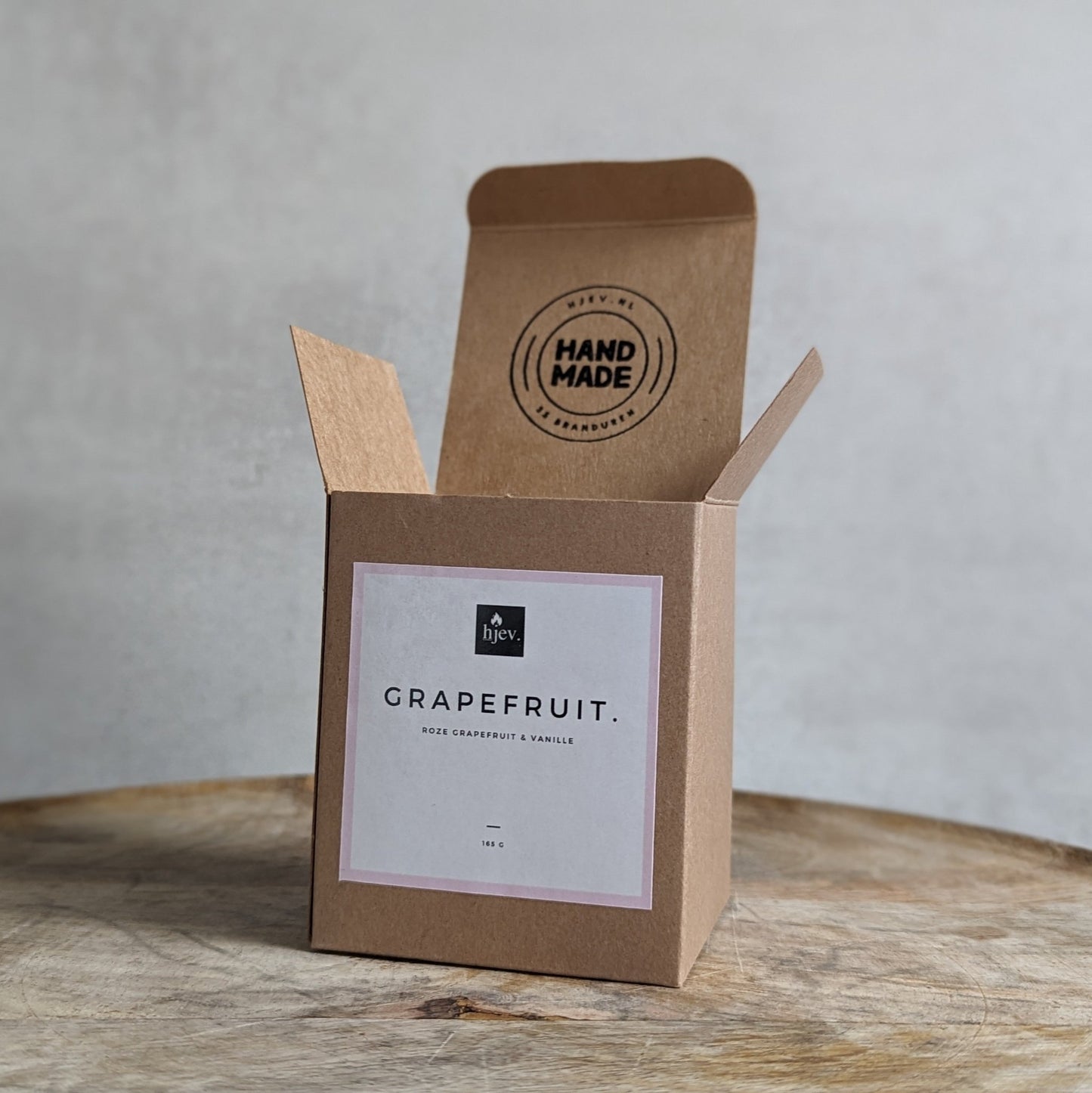 Een close-upafbeelding van de Grapefruit geurkaars van HJEV, gepresenteerd in een levendige en kleurrijke verpakking. De kaars verspreidt een verfrissende en energieke geur, geïnspireerd door de sappige en sprankelende aroma's van grapefruit, waardoor een opwekkende en stimulerende sfeer in huis wordt gecreëerd.