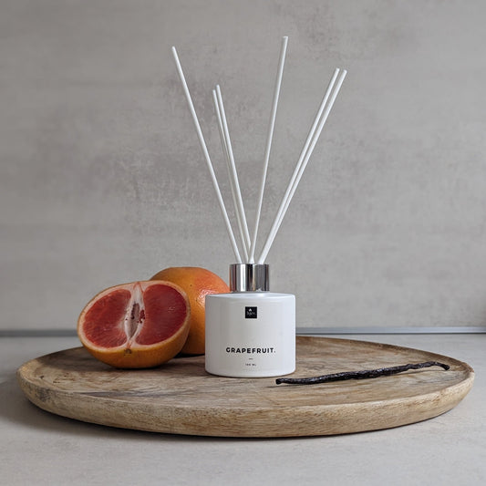 Een close-upafbeelding van de Grapefruit & Vanille geurstokjes van HJEV, gepresenteerd in een milieuvriendelijke verpakking. De geurstokjes verspreiden een verfrissende en energieke geur, waarbij de sprankelende aroma's van grapefruit perfect samengaan met de warme en zoete tonen van vanille, waardoor een opwekkende en stimulerende sfeer in huis wordt gecreëerd.