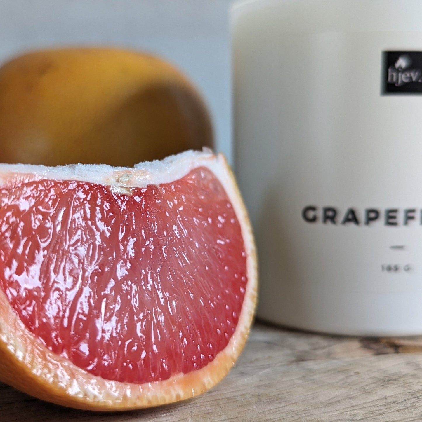 Een close-upafbeelding van de Grapefruit & Vanille geurkaars van HJEV, gepresenteerd in een levendige en kleurrijke verpakking. De kaars verspreidt een verfrissende en energieke geur, waarbij de sprankelende aroma's van grapefruit perfect samengaan met de warme en zoete tonen van vanille, waardoor een opwekkende en stimulerende sfeer in huis wordt gecreëerd.